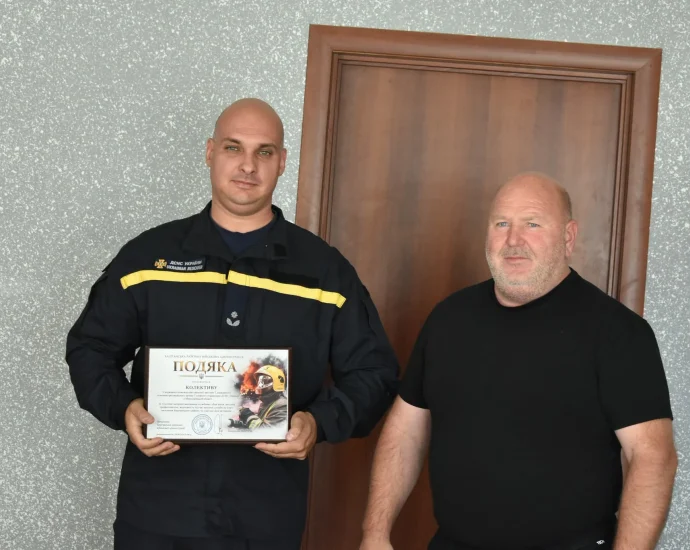 Рятувальник ДСНС у формі тримає подяку Баштанської РВА біля чоловіка в чорному