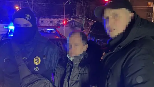 Поліцейські затримують людину біля машин з мигалками вночі