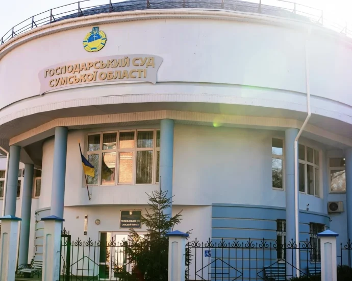 Біла кругла будівля Господарського суду Сумської області з прапором України