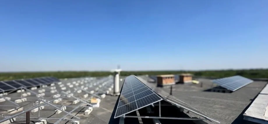Сонячні панелі на плоскому даху на металевих опорах під блакитним небом