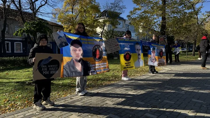 Люди тримають плакати з портретами зниклих військових на вулиці восени