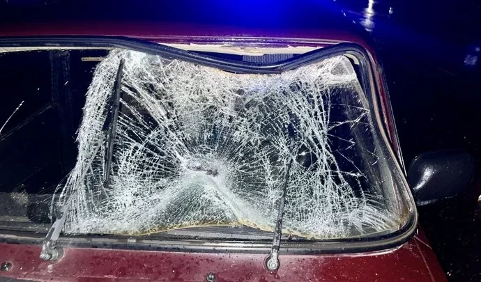 Розбите лобове скло бордового автомобіля вночі біля синіх проблискових вогнів