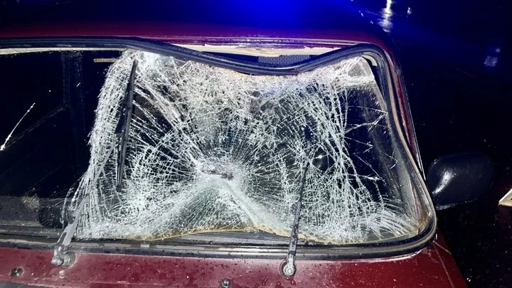 Розбите лобове скло бордового автомобіля вночі біля синіх проблискових вогнів
