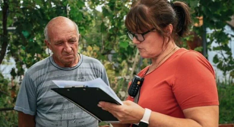 Жінка з планшетом і рацією разом із чоловіком переглядають документи надворі