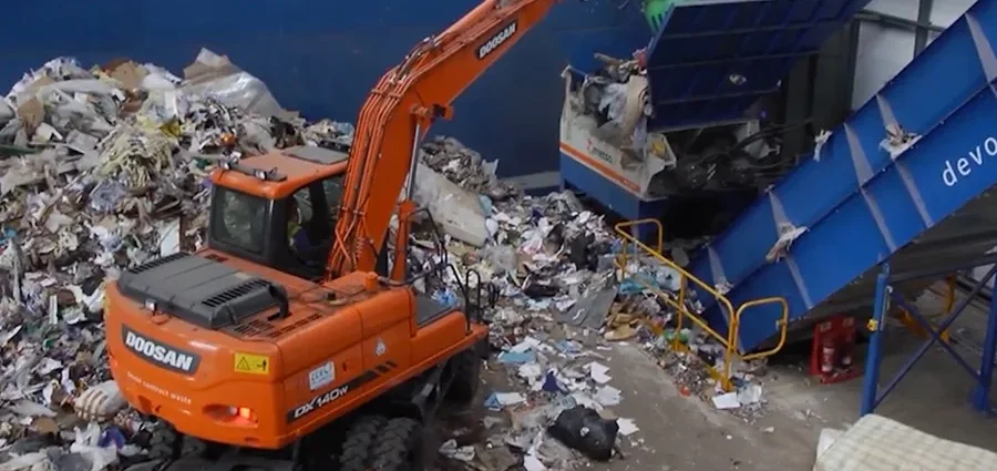 Помаранчевий екскаватор Doosan завантажує змішані відходи в синій конвеєр сортувальної лінії
